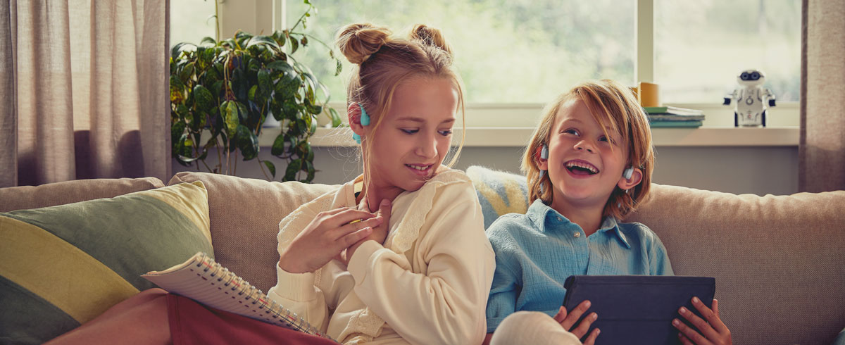 Copii bucur&acirc;ndu-se de un videoclip utiliz&acirc;nd căştile Philips cu design deschis pentru copii